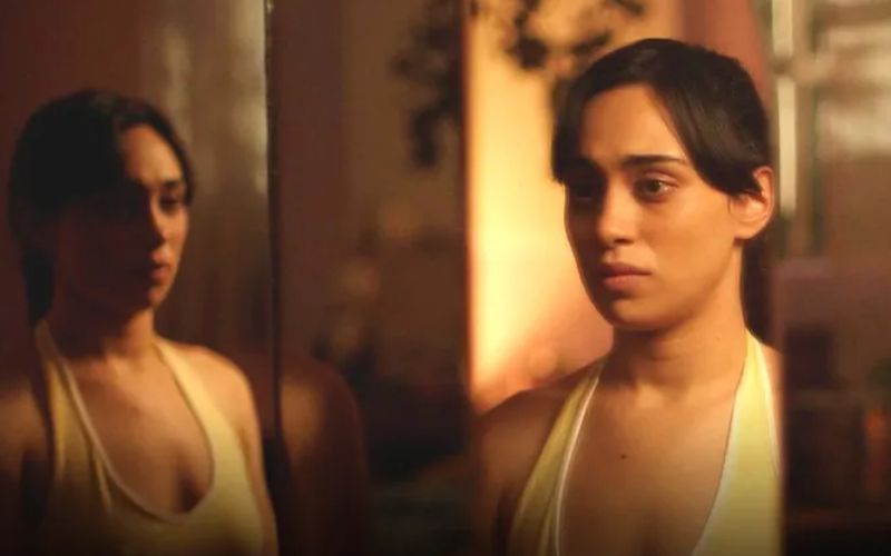 Fotograma de la película Huesera de Michelle Garza Cervera, con una mujer observando su reflejo con expresión inquieta.