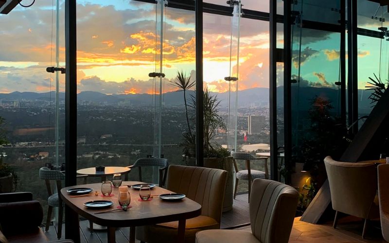 Interior del restaurante Ling Ling en Chapultepec Uno con ventanales y vista panorámica de la Ciudad de México al atardecer.