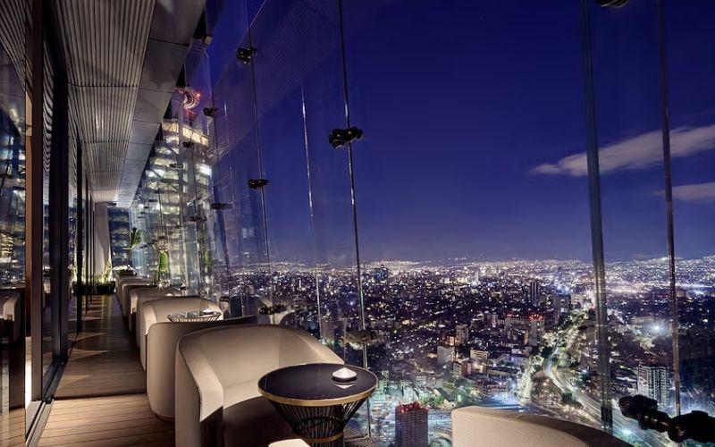 Terraza del restaurante Samos en The Ritz-Carlton México City con vista panorámica nocturna de Paseo de la Reforma.