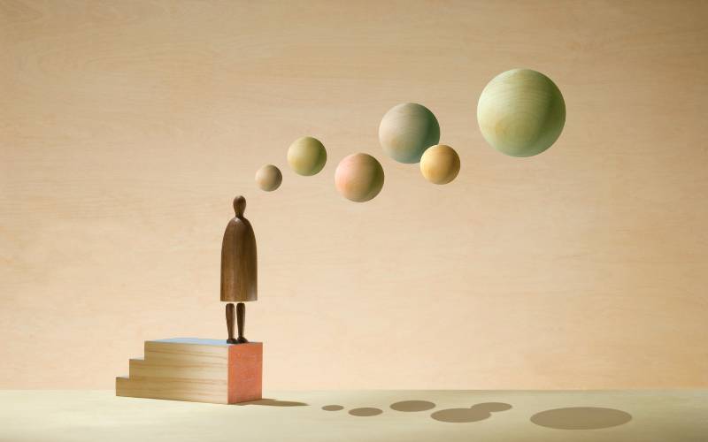 Figura humana observando esferas flotantes que simbolizan pensamientos y recuerdos reconstruidos por la mente.
