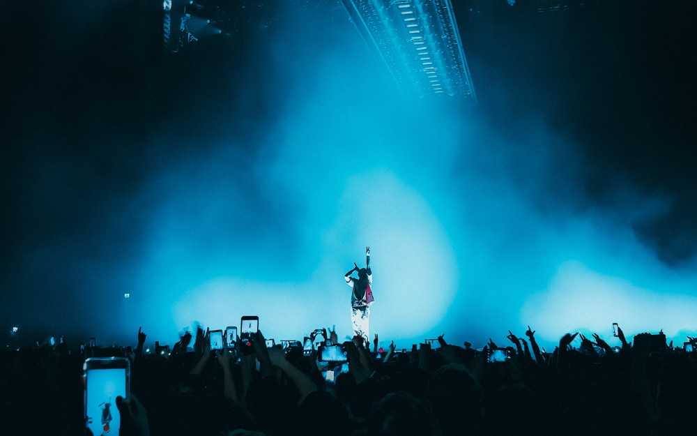 Multitud cantando y saltando en un festival de música con luces azules para despedir el 2025 en México