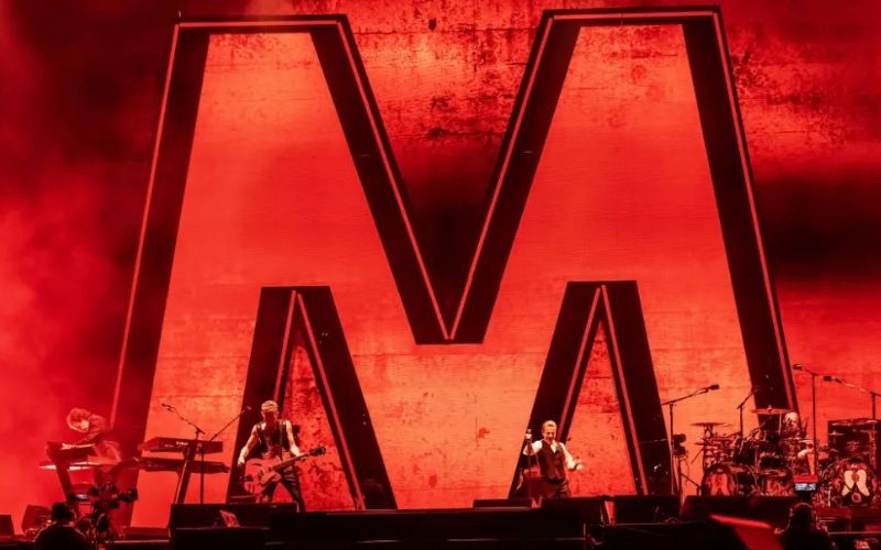 Depeche Mode en el escenario del Foro Sol frente a una gran letra M roja, escena del documental Depeche Mode: M filmado en México.