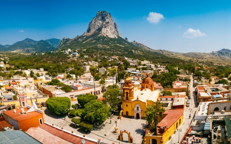 Vista aérea del pueblo mágico de Bernal con la Peña de Bernal al fondo y su iglesia principal en primer plano.