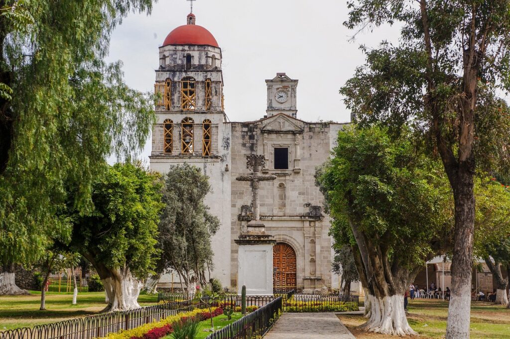 Fachada del ex convento agustino de Malinalco rodeado de árboles y jardines en el centro del pueblo mágico.