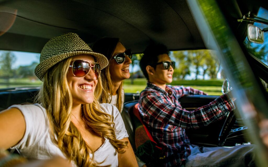 Grupo de amigos sonrientes viajando en auto rumbo a pueblos mágicos cerca de la CDMX.