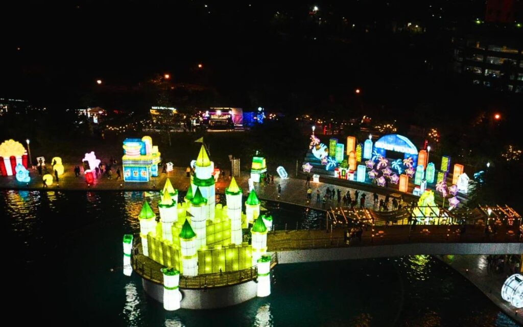 Vista nocturna de Luztopía en Parque Fundidora, Monterrey, con castillo iluminado, figuras navideñas y recorrido de luces sobre el agua.