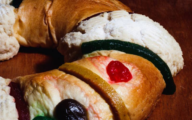 Detalle de Rosca de Reyes con frutas cristalizadas de colores que simbolizan las joyas de los Reyes Magos sobre la superficie del pan.