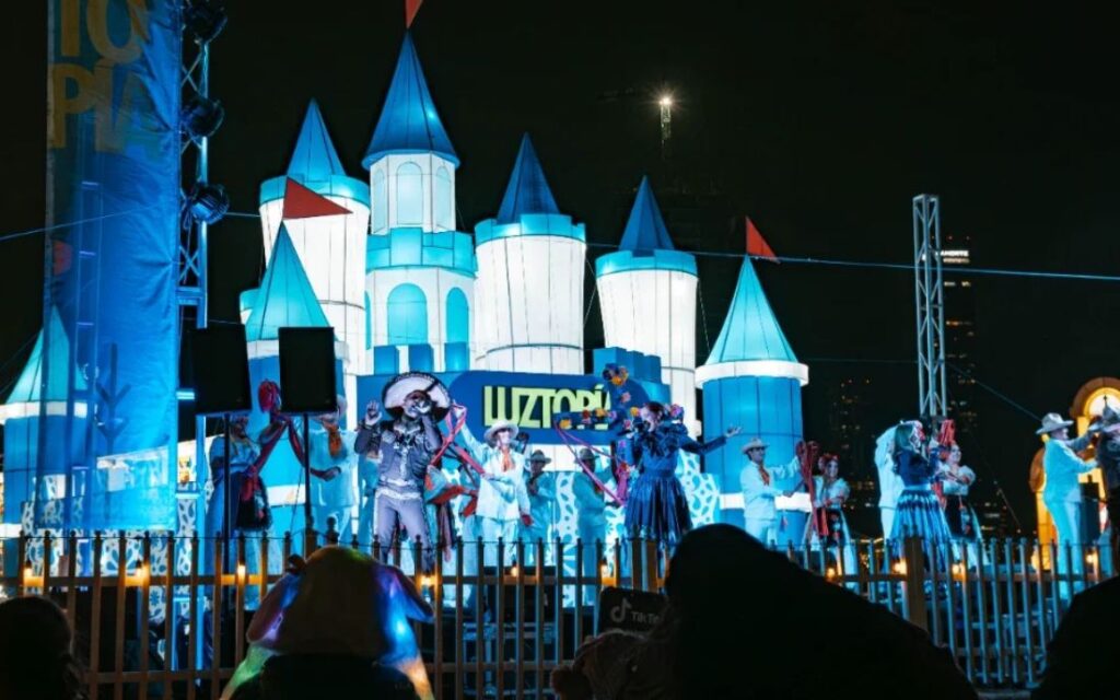 Espectáculo en Luztopía Monterrey con escenario iluminado, castillo de luces y presentación musical frente a visitantes durante la temporada navideña.