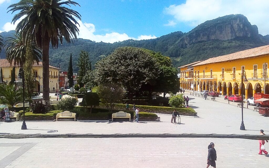 Plaza de Armas de Tlatlauquitepec, Pueblo Mágico de Puebla, rodeada de portales, vegetación y el Cerro Cabezón al fondo